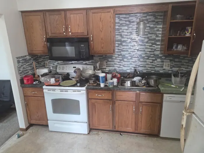 A kitchen counter and stove buried in clutter