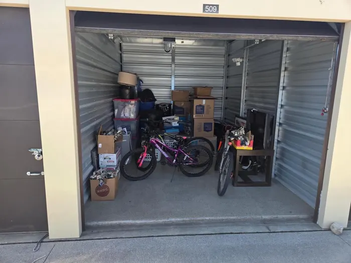 A storage unit full of boxes, bikes and furniture