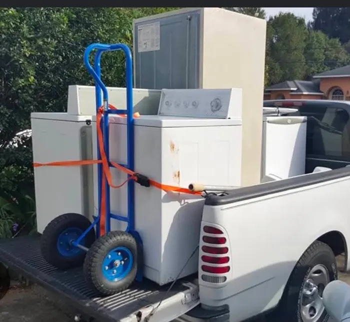 A pickup loaded with a washer, dryer and refrigerator strapped down